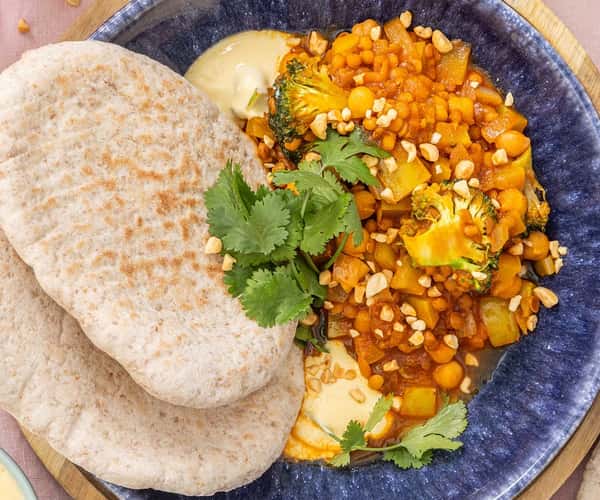 Curry med kikerter og garam masala, fullkornspita, mangodressing og peanøtter