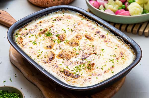 Gratinerte fiskeboller i hvit saus med blomkål, grønne erter og gressløk
