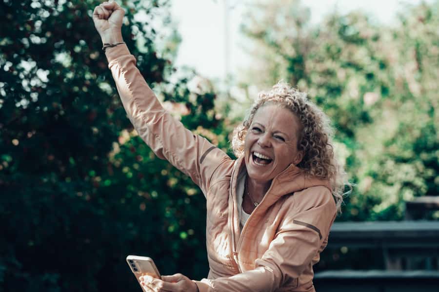 Jeanette Roede jubler utendørs med mobiltelefon